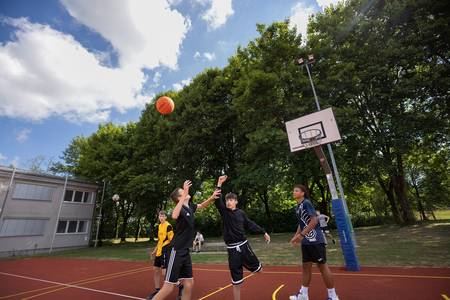 Auf dem Sportplatz spielen Jungs Basketball.